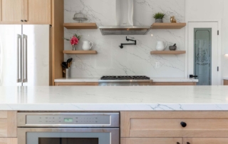 11 common kitchen renovation mistakes to avoid. Image of a freshly done kitchen with natural wood colored cabinets, white counters, and an oven/stove.